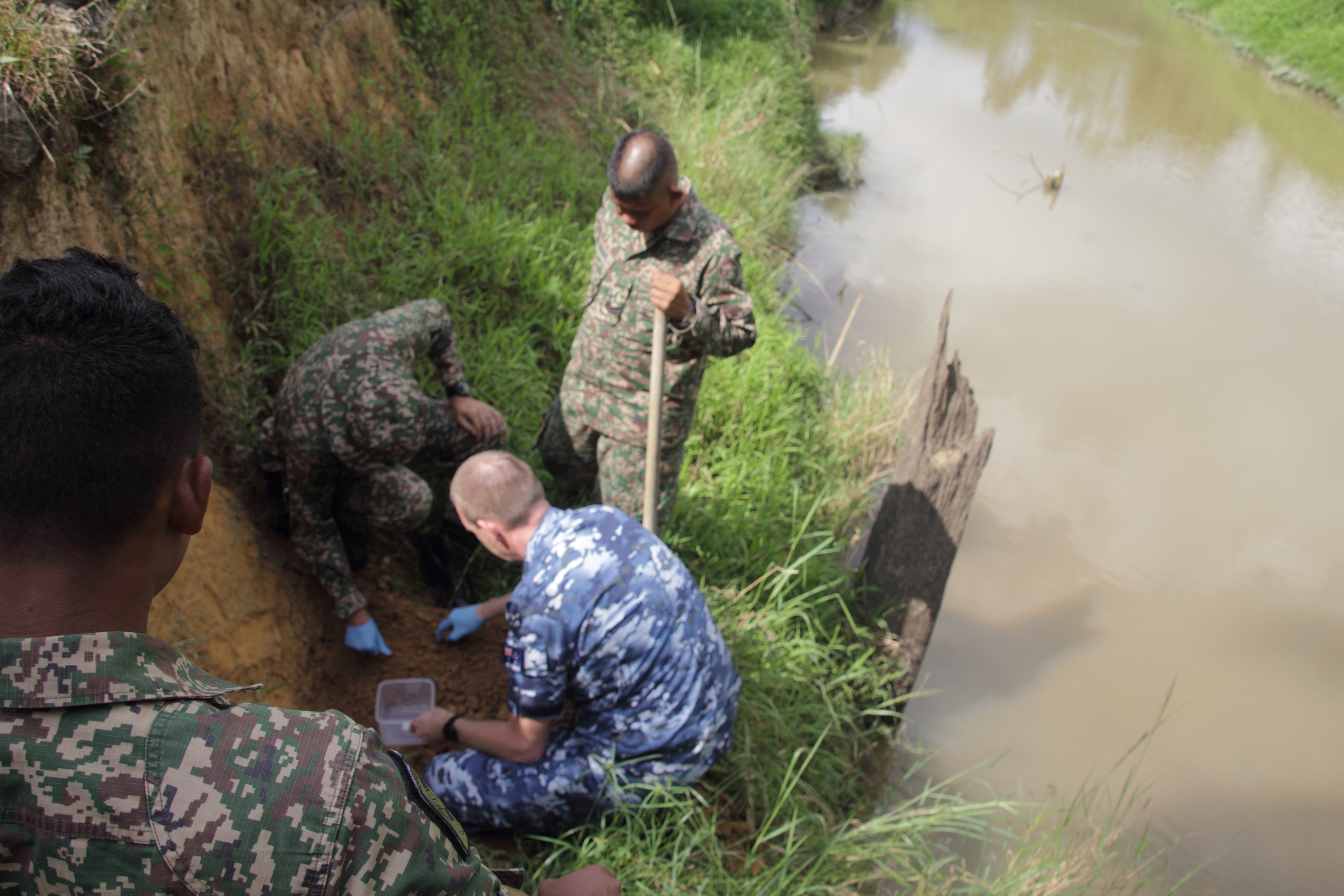 Several military personnel collect soil in Gemas, Malaysia.